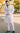 Shadab Khan wearing a white kurta and pants with embroidery on the chest and pocket, standing outdoors.