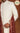 White embroidered sherwani with red shawl on a brown background